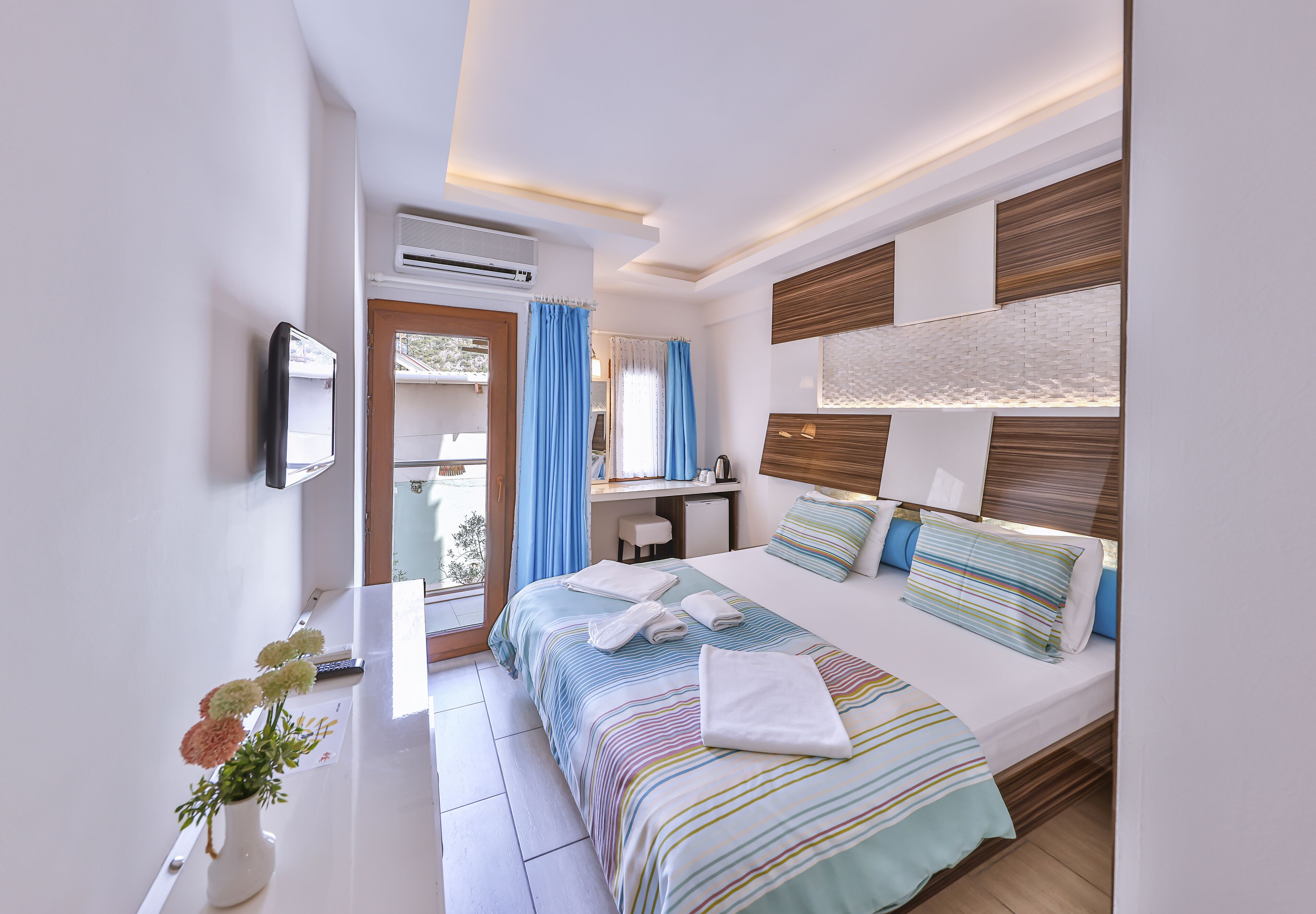 Una habitación de hotel moderna con cama, mesita de noche y un pequeño escritorio.