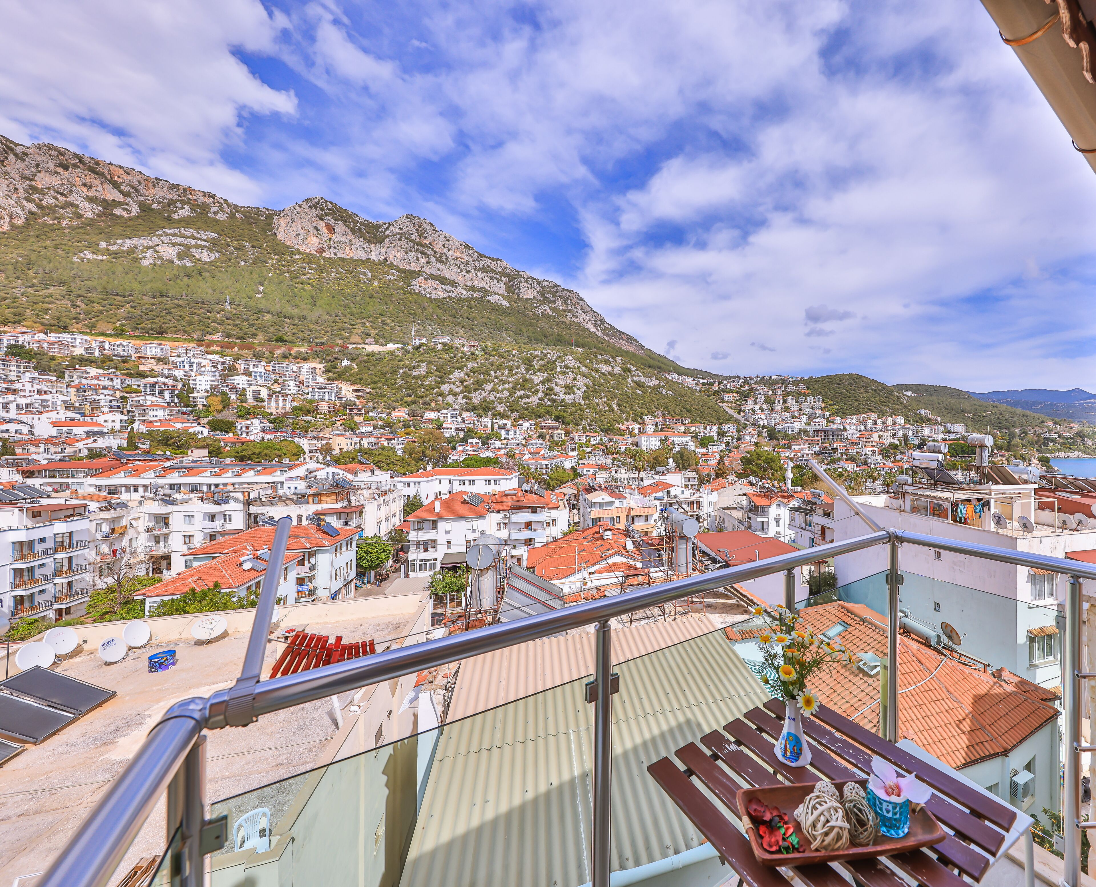 Un balcón con vistas a un pueblo costero, que incluye casas escalonadas, una montaña y cielo despejado.