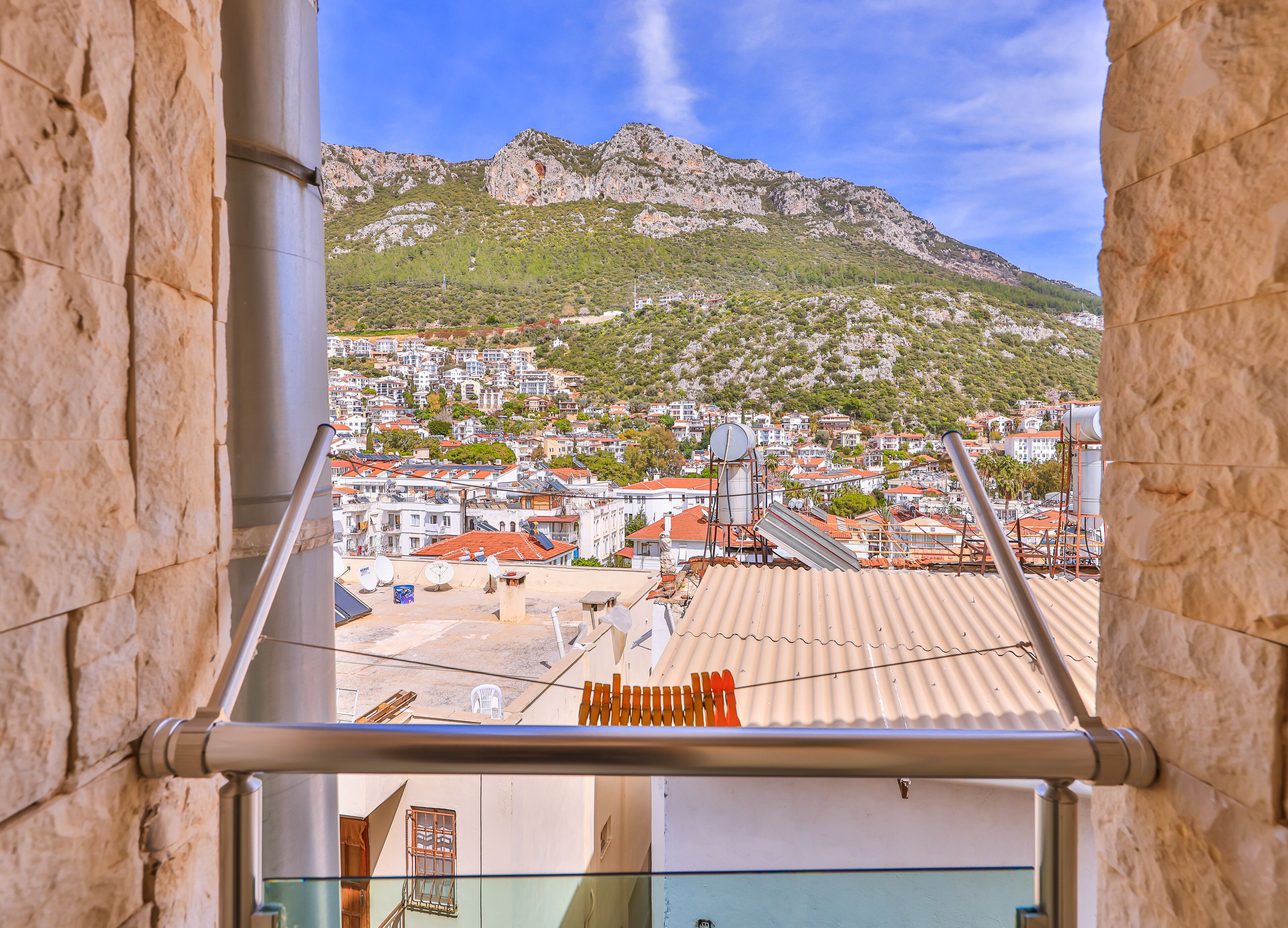 Vista de uma varanda com vista para uma cidade, com edifícios e uma montanha ao fundo.