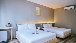 A hotel room with two beds, a small table with a kettle, a wall-mounted air conditioner, and a painting on the wall. - Canary Hotel (Kuala Lumpur)