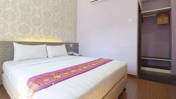 Habitación de hotel con cama, cabecera, aire acondicionado, armario y papel tapiz estampado.