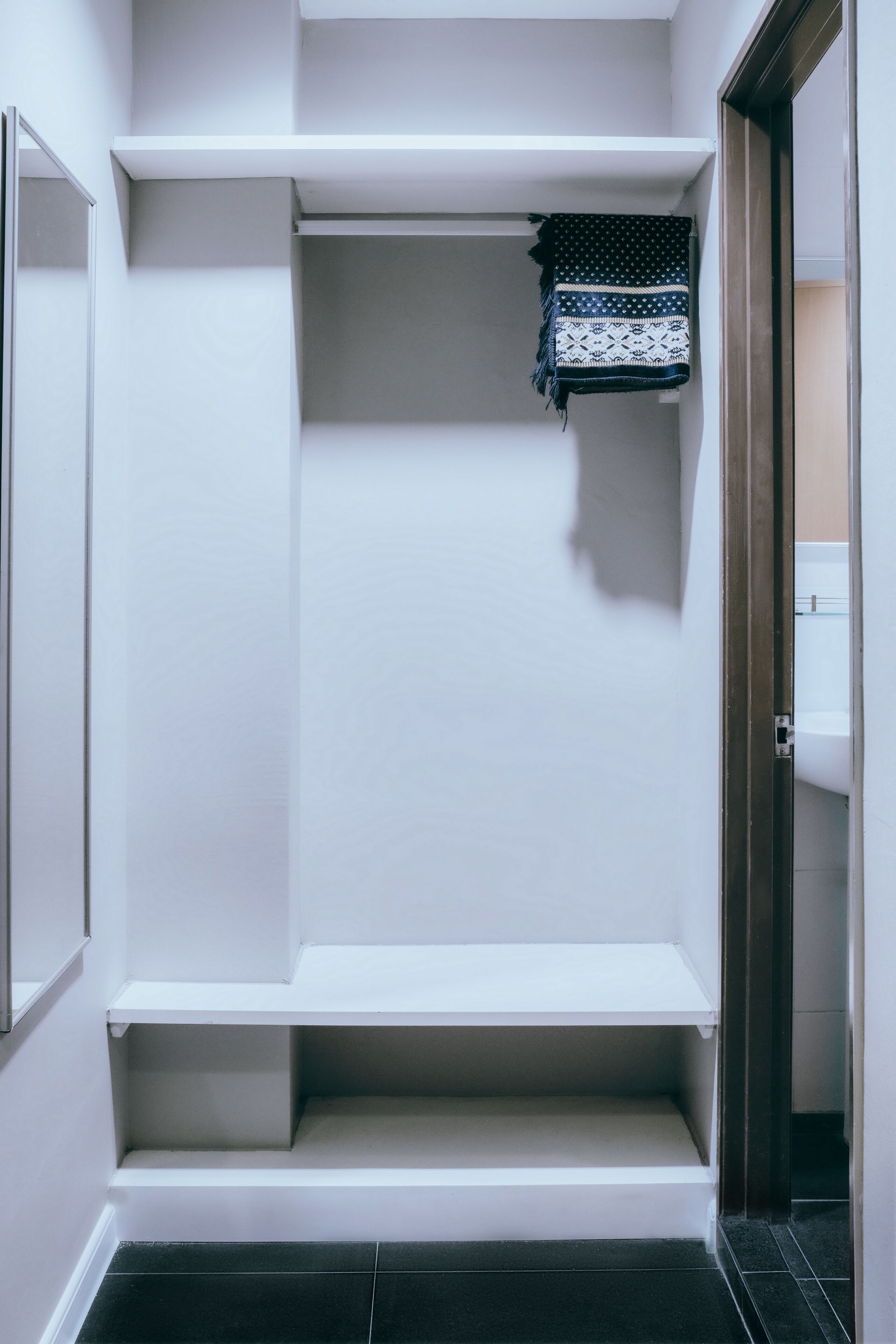 A walk-in closet with white shelving units and a hanging rack.