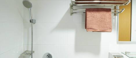 A bathroom with a shower, a towel rack with two towels, a glass soap dish, and a toilet.