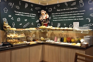A café counter with a variety of pastries and baked goods displayed in glass cases and baskets. - Pousada Stillo Gramado (Gramado)