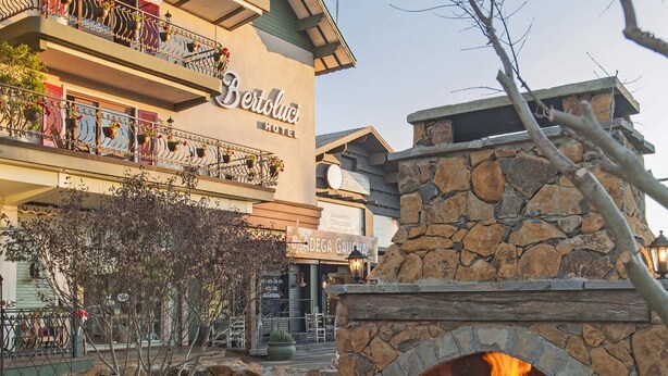 A hotel with a stone fireplace, outdoor seating, and a balcony with plants. - Hotel Bertoluci (Gramado)