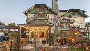 A hotel with a green facade, multiple balconies, and outdoor seating areas. - Hotel Bertoluci (Gramado)