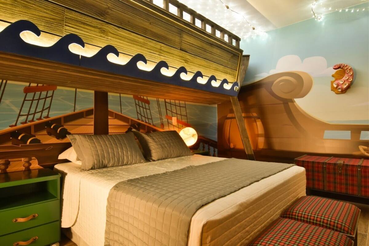 A bedroom with a nautical theme, including a ship's wheel headboard, a bed with a quilted blanket, and a green nightstand.