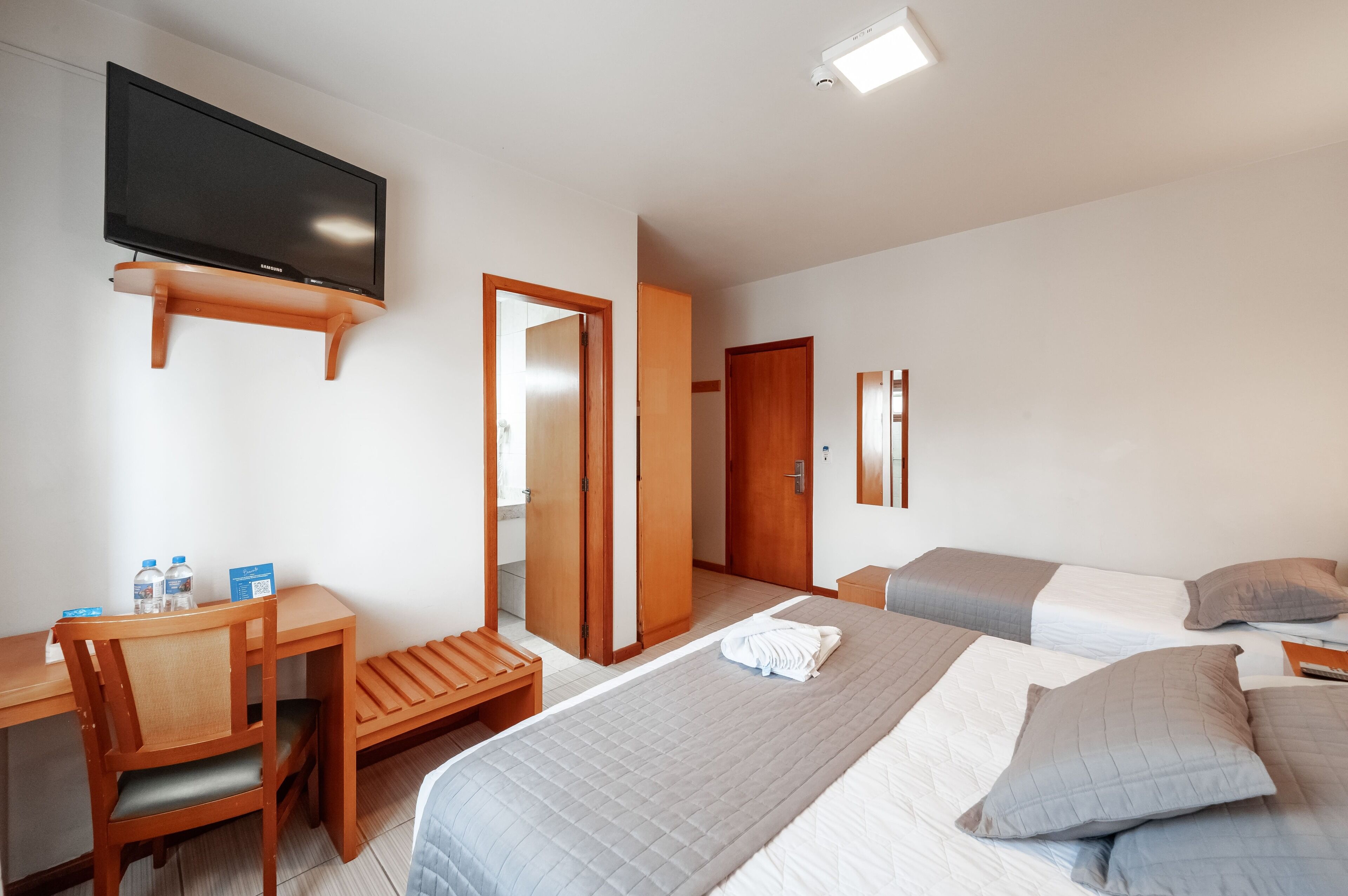 A hotel room with a bed, a desk, a chair, a television, and a bathroom.