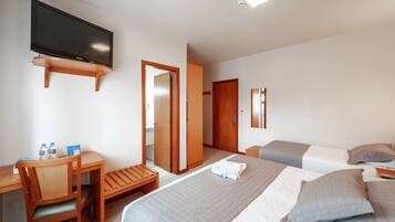 A hotel room with a bed, a desk, a chair, a television, and a bathroom.