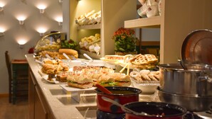 A buffet with various food items and a pot of soup. - Hotel Bertoluci (Gramado)
