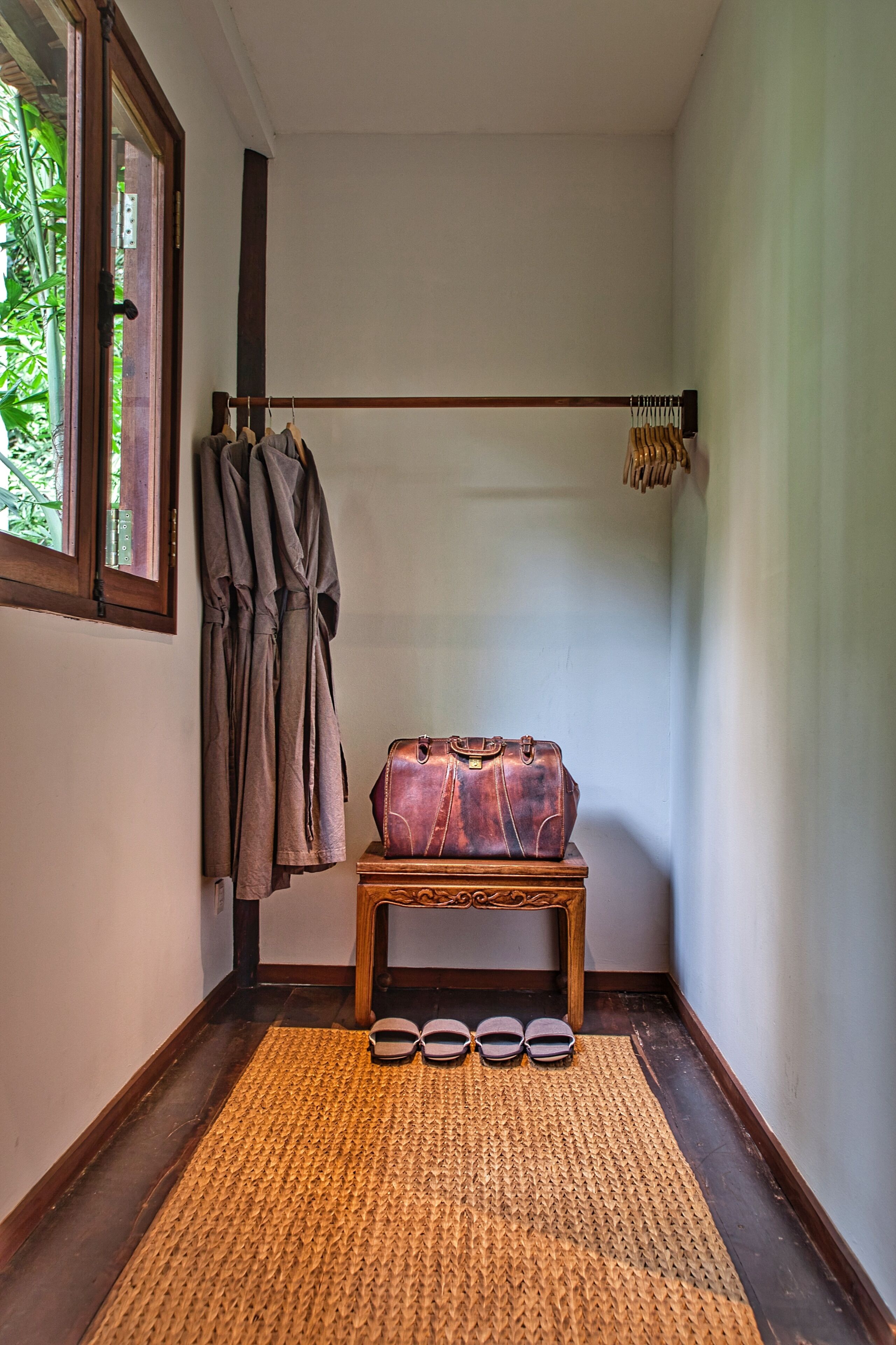 Una habitación de esquina con un banco de madera, un par de gafas de sol y un perchero.