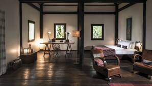 Una habitación con una cama, dos sillas, un escritorio y una lámpara.