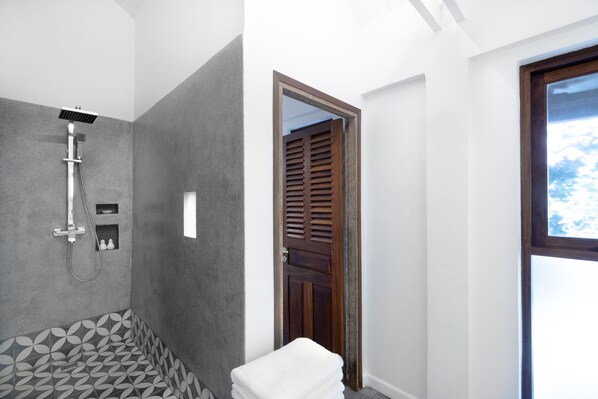 A modern bathroom with a shower, a patterned floor, and a wooden door.
