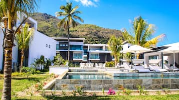 Un complexe hôtelier moderne doté d’une piscine, de palmiers et offrant une vue sur un paysage montagneux.