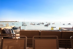 Una terraza con vista al mar, con un sofá y sillones.