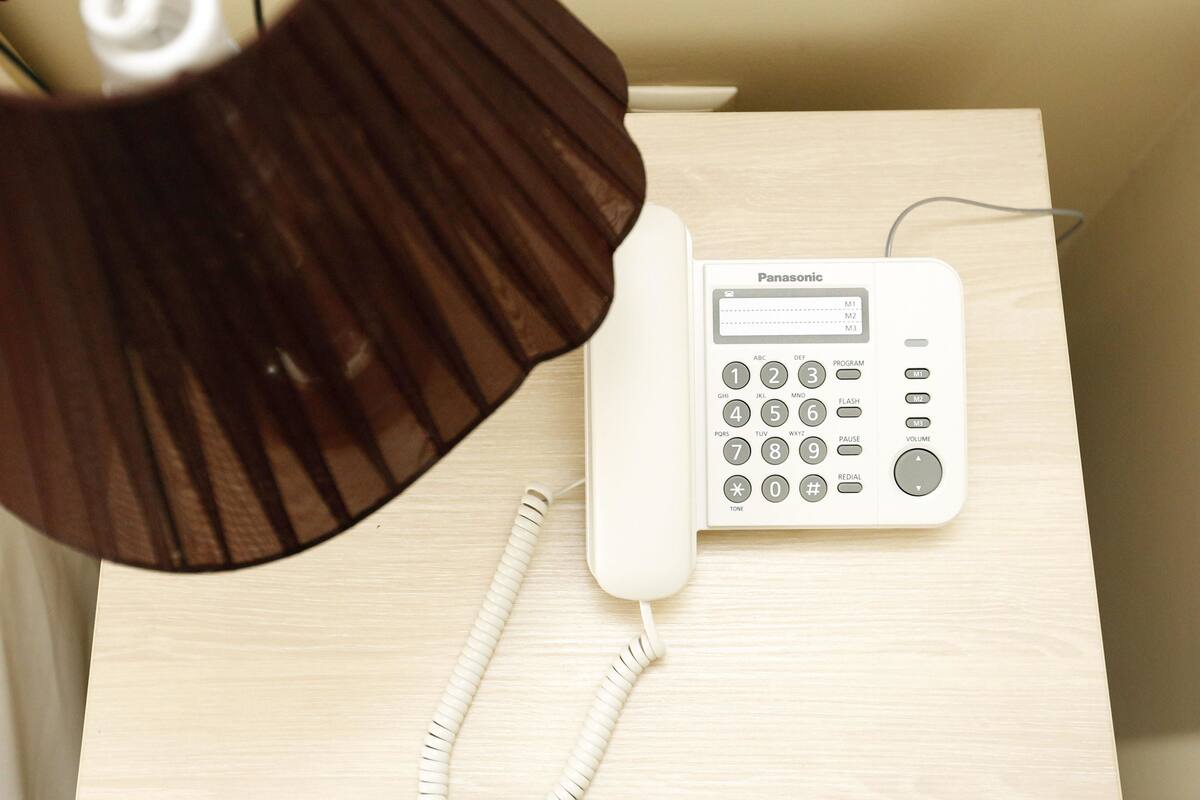 Un teléfono inalámbrico Panasonic sobre una mesita de noche de madera.