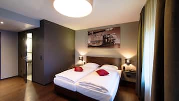 A hotel room with a double bed, two bedside tables with lamps, a large circular light fixture, and a painting on the wall.