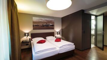 A hotel room with two beds, a large window, and a painting of a ship on the wall.