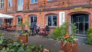 A brick building with a sign reading "Hotel Volschule." There are outdoor tables and chairs, and a planter with flowers in front. - Hotel Volksschule (Hamburg)