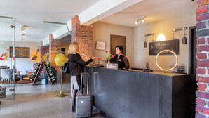 A reception area with a modern design, including a brick wall, a reception desk, and a glass partition. - Hotel Volksschule (Hamburg)
