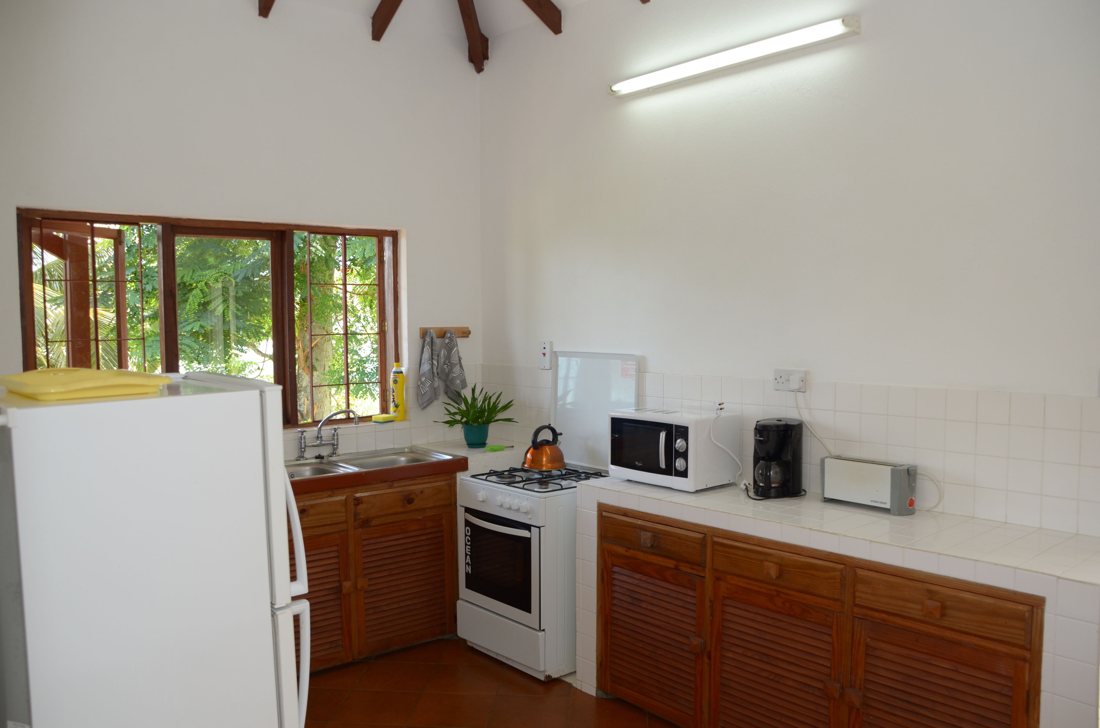 A compact kitchen with a refrigerator, stove, microwave, and toaster.