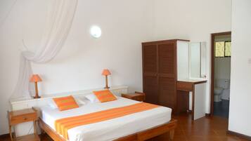 Une chambre à coucher avec un lit, des tables de chevet, une armoire et une salle de bain visible à travers une porte ouverte.