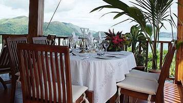 A dining table set for four with a white tablecloth, surrounded by wooden chairs.