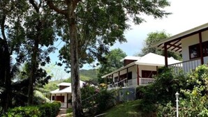 A two-story building with a balcony, surrounded by lush greenery and trees. - La Residence (Mahé Island)