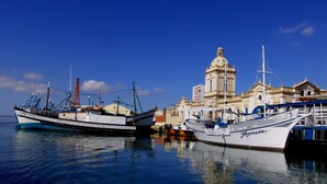 Two boats docked at a harbor with a prominent building in the background. - Hotel Atlantico Rio Grande (Rio Grande)