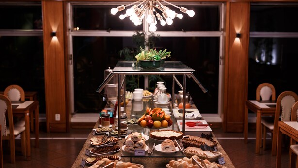 A buffet setup with various food items and a central decorative plant on a glass table. - Hotel Atlantico Rio Grande (Rio Grande)