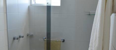 Un baño con ducha vidriada, inodoro y perchero para toallas.