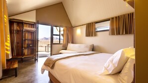 A bedroom with a large bed, a wooden bench, a wardrobe, and a view of the outdoors. - Desert Quiver Camp (Sesriem)
