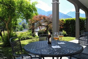 A round metal table with two chairs, a bottle of beer, and two glasses of beer on a patio with a mountain view. - Hotel Internazionale (Domodossola)