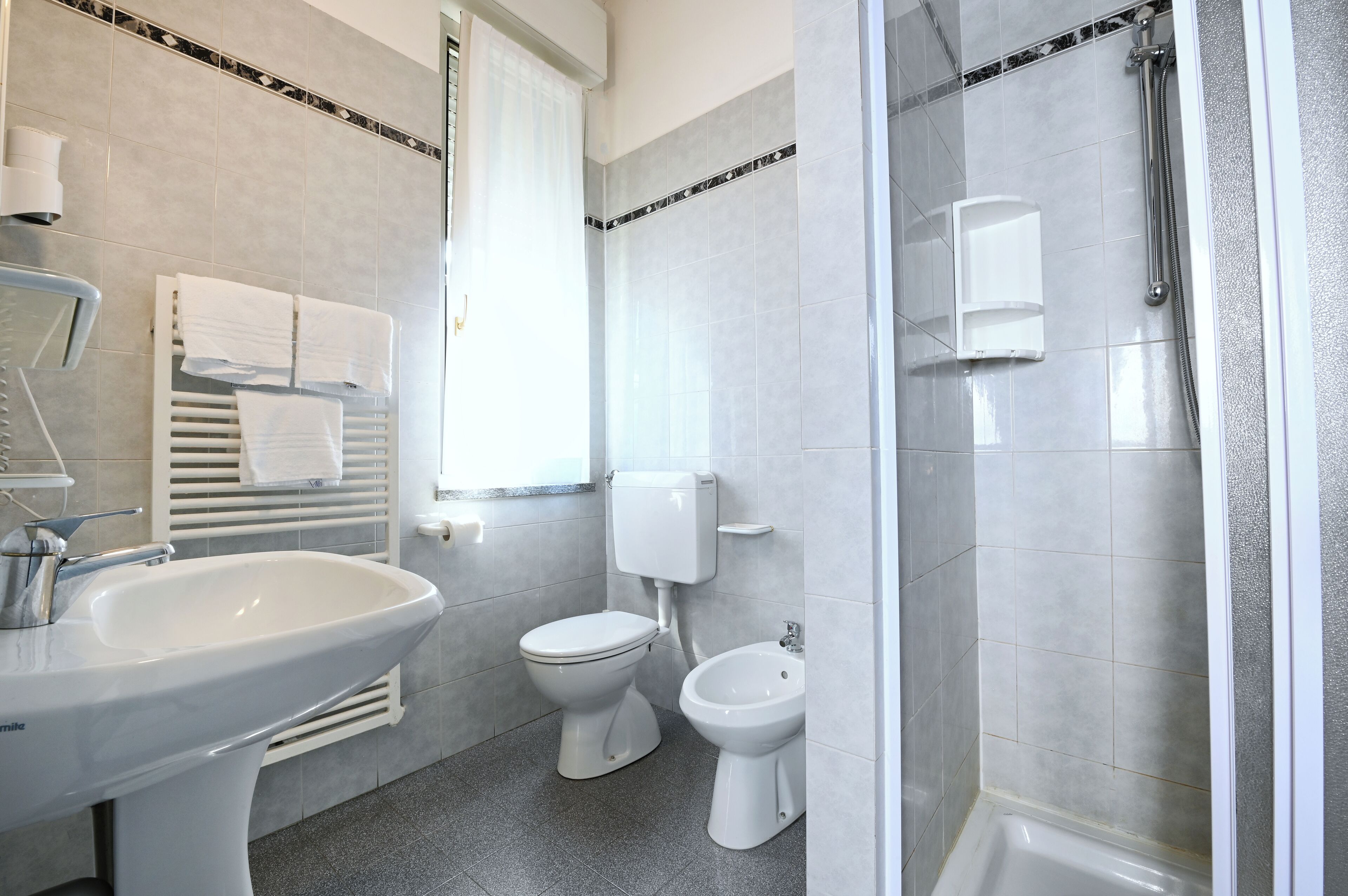 Un baño moderno con lavabo, inodoro, bidé y ducha.