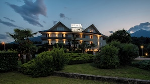 Un hotel con un llamativo letrero que dice 'HOTEL', rodeado de follaje cuidado y un paisaje montañoso.