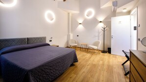 Un dormitorio moderno con una cama grande, un escritorio, dos sillas y un armario.
