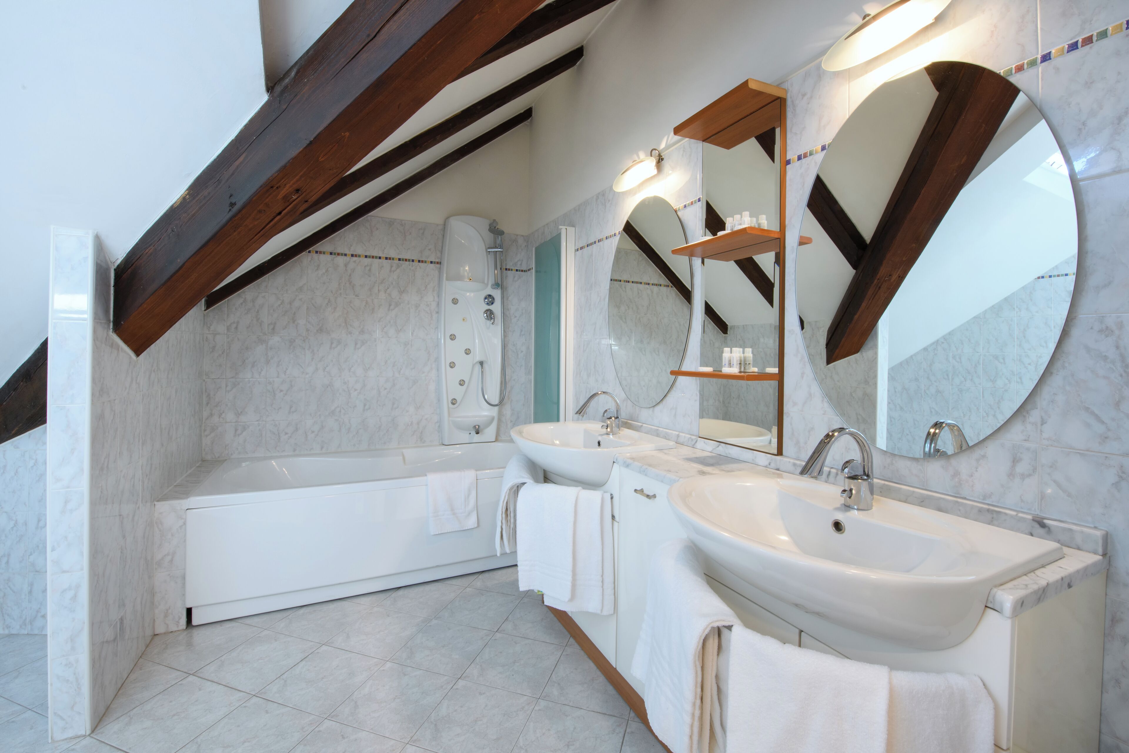 Un baño moderno con bañera, dos lavamanos y un espejo grande.