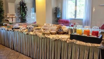Un buffet proposant une variété de plats et de boissons, une plante en pot et une fenêtre avec des rideaux.