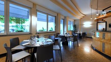 A restaurant with multiple dining tables, chairs, and a counter.
