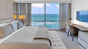 Una habitación de hotel moderna con una cama grande, un escritorio y vistas al océano.