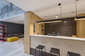 A modern interior with a reception desk, bar area, and seating. - Puerto Limon Hostel (Buenos Aires)