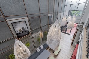 Un interior moderno con techo alto, diseño geométrico en la pared y lámparas colgantes.