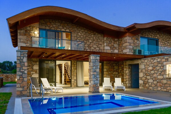 A two-story stone house with a swimming pool, outdoor seating, and a covered patio area. - Estrella Villas (Rhodes)