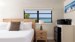 A hotel room with a bed, a nightstand with a lamp, a microwave, and a refrigerator. - Conch Key Fishing Lodge and Marina (Marathon)
