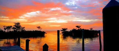 A sunset over a calm body of water with a wooden dock extending into the water.