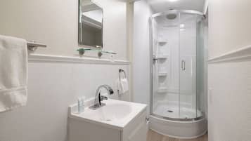 A modern bathroom with a white sink, a glass-enclosed shower, and a mirror above the sink.