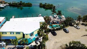 A coastal hotel with a pool, parked cars, and a view of the ocean. - Conch Key Fishing Lodge and Marina (Marathon)