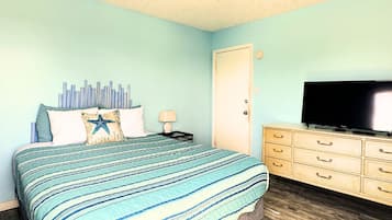 A bedroom with a bed, a dresser, a television, and a ceiling fan.