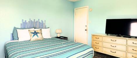 A bedroom with a bed, a dresser, a television, and a ceiling fan.