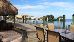 A wooden deck with tables and chairs overlooking a body of water, with boats docked nearby. - Conch Key Fishing Lodge and Marina (Marathon)